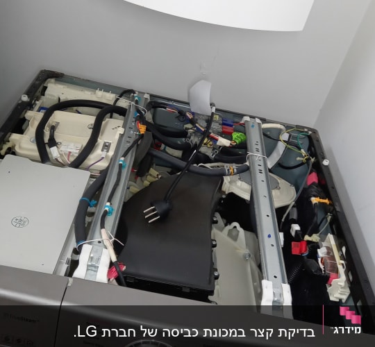 מכונת כביסה פתוחה עם חוטי חשמל פנימיים